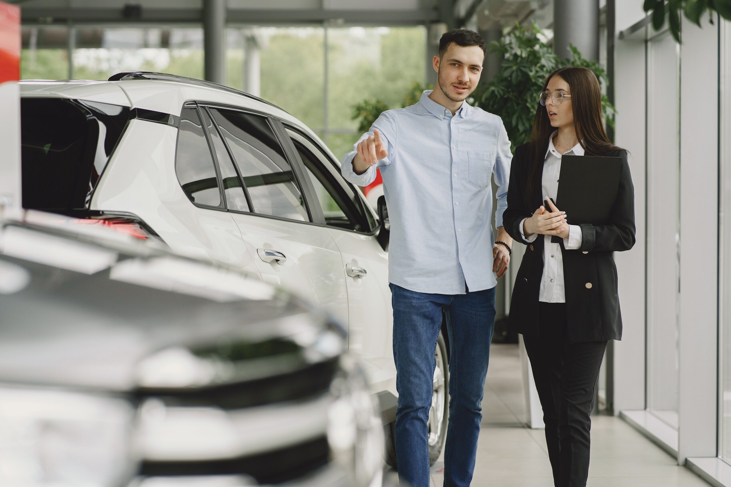 A girl and boy walking beside the car to check the eligibility of refinancing